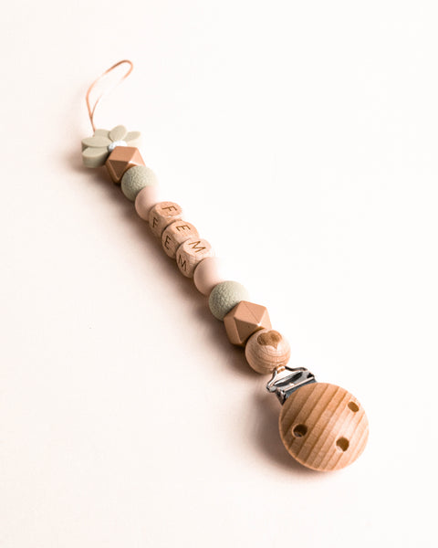 Fopspeen ketting met houten kraal met hartje en licht groen bloemetje.