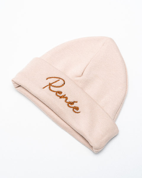 beige babymuts met naam geborduurd in bruine letters