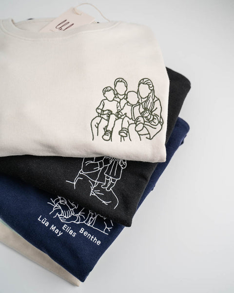 stapel met gepersonaliseerde truien met lijntekeningen die geborduurd werden van een foto