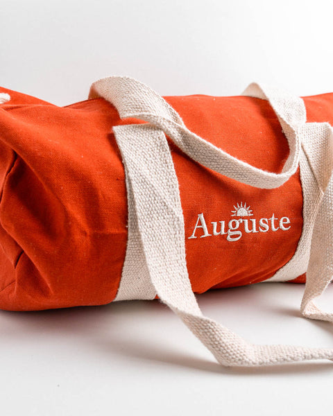 gepersonaliseerde rode logeertas met naam auguste geborduurd met het lettertype en icoontje van het geboortekaartje