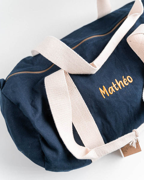 gepersonaliseerde donkerblauwe logeertas met naam geborduurd in oranje letters