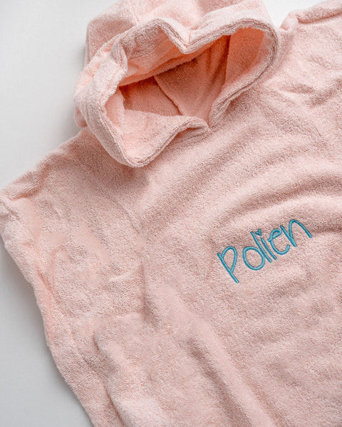 roze poncho met naam geborduurd in felblauwe letters