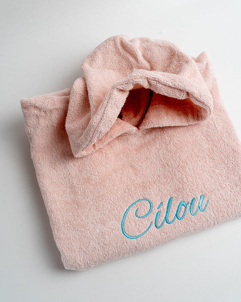 gepersonaliseerde roze poncho met de naam Cilou geborduurd in blauwe sierletters
