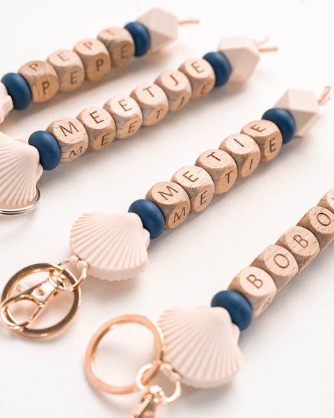 gepersonaliseerde sleutelhanger met houten letterkralen en figuurtje van een schelp